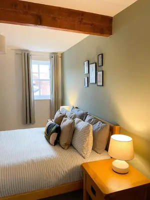 a bedroom with a bed with pillows and a table at Hadrians Retreat, Cosy 1 Bed Flat - near M6 Jct45, A75, Gretna & Carlisle in Longtown