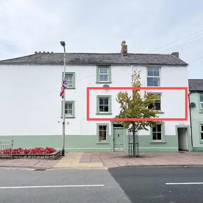 a white and green building with a red stripe on it at Hadrians Retreat, Cosy 1 Bed Flat - near M6 Jct45, A75, Gretna & Carlisle in Longtown
