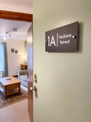 a sign hanging on a wall in a living room at Hadrians Retreat, Cosy 1 Bed Flat - near M6 Jct45, A75, Gretna & Carlisle in Longtown