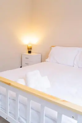a bedroom with a white bed and a night stand at Your Perfect Home Away From Home in Workington