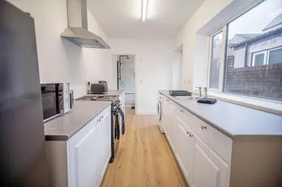 a kitchen with white cabinets and a large window at Your Perfect Home Away From Home in Workington
