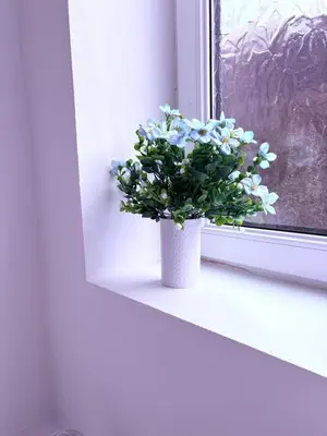 a white vase with blue flowers sitting on a window sill at Your Perfect Home Away From Home in Workington