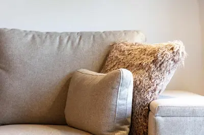 a couch with a throw pillow on it at Old Prestwick Point - Donnini Apartments in Prestwick