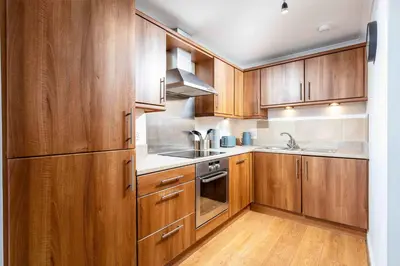 a kitchen with wooden cabinets and stainless steel appliances at Old Prestwick Point - Donnini Apartments in Prestwick
