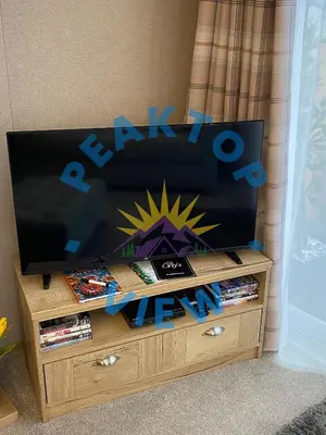 a flat screen tv sitting on top of a wooden entertainment center at Peaktop View, Winscales, near Cockermouth Cumbria in Winscales