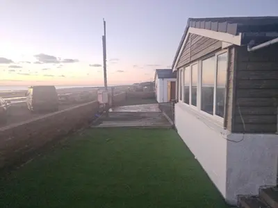 a house with a yard of grass next to a building at Sandylands in Braystones