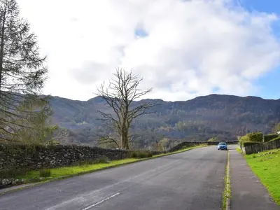 a car driving down a road with mountains in the background at Quarry's Edge in Chapel Stile