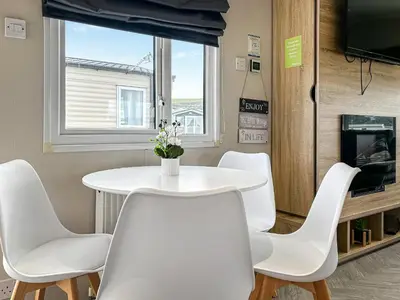 a white table and chairs in a room with a window at Coastal Bay View in Ayr