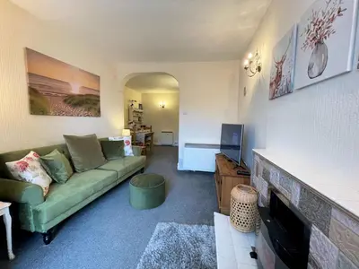 a living room with a green couch and a fireplace at Pass the Keys Cosy Romantic Getaway with Hot Tub in Whithorn