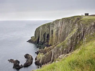 a cliff next to the ocean with a house on top at Pass the Keys Cosy Romantic Getaway with Hot Tub in Whithorn