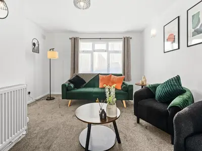 a living room with a green couch and a table at Edison House - Comfy Stay in Stafford in Moffat