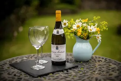a bottle of wine and a glass on a table with a vase at 1 Bed in Uldale oc-g34032 in Uldale