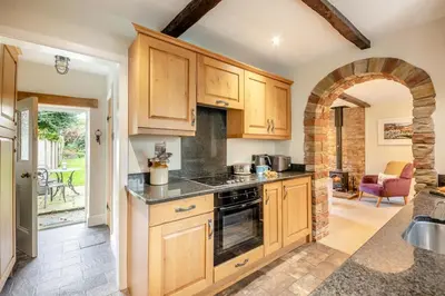 a kitchen with wooden cabinets and an archway at 1 Bed in Uldale oc-g34032 in Uldale