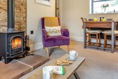 a living room with a wood stove and a chair at 1 Bed in Uldale oc-g34032 in Uldale