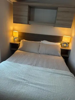 a bedroom with a bed with two lights on it at Luxury Seafront 3 Bedroom Caravan in Minishant