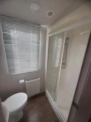 a bathroom with a toilet and a glass shower at Luxury Seafront 3 Bedroom Caravan in Minishant
