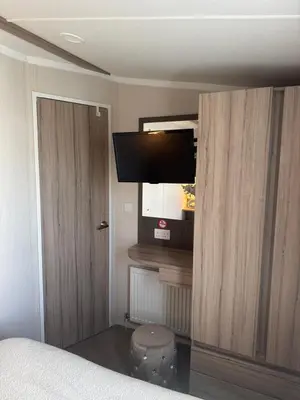 a bedroom with a bed and a flat screen tv at Luxury Seafront 3 Bedroom Caravan in Minishant