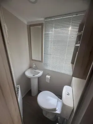 a small bathroom with a toilet and a sink at Luxury Seafront 3 Bedroom Caravan in Minishant