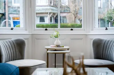 a room with two chairs and a table with a vase on it at Newlands House - Quiet Keswick Retreat with Stunning Fell Views, Walk to Town in Keswick