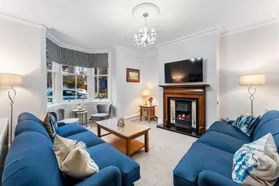 a living room with a blue couch and a fireplace at Newlands House - Quiet Keswick Retreat with Stunning Fell Views, Walk to Town in Keswick