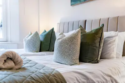 a bed with green and white pillows on it at Newlands House - Quiet Keswick Retreat with Stunning Fell Views, Walk to Town in Keswick