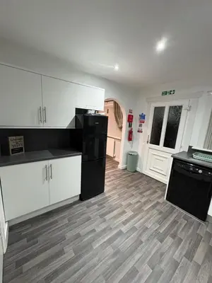 a kitchen with white cabinets and a black refrigerator at 100 Castle in New Cumnock