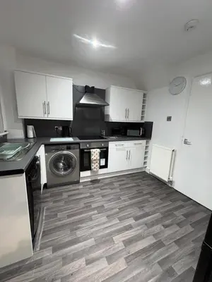 a kitchen with white cabinets and a washing machine at 100 Castle in New Cumnock