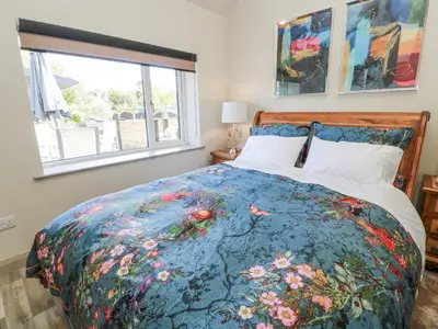 a bedroom with a bed with a floral bedspread at Scotia At The Brig in Annan