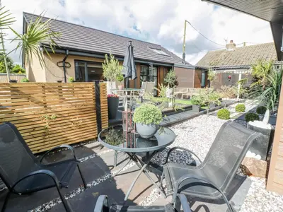 a patio with chairs and a table and a fence at Cabin At The Brig in Annan