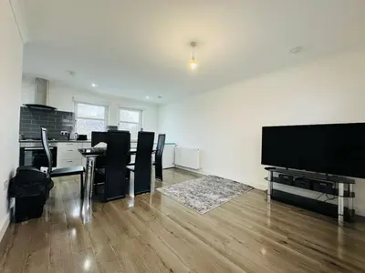 a living room with a dining table and a flat screen tv at 3 bedroom luxury Apartment in Prestwick