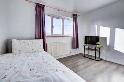 a white bedroom with a bed and a television at Southend perfect Stays in Moffat