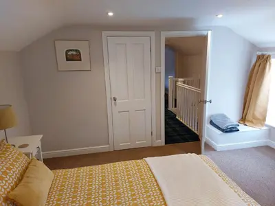 a bedroom with a bed and a hallway with a staircase at The Coach House- Canonbie in Canonbie