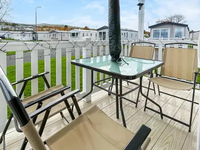 a glass table and chairs on a balcony at H And D Greenan Village in Ayr