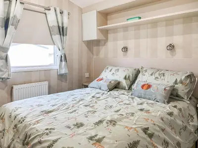 a bedroom with a bed with a comforter and a window at H And D Greenan Village in Ayr