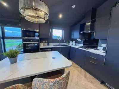 a kitchen with blue cabinets and a white counter top at Blackthorn Timber Lodge in Bothel