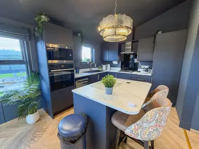 a kitchen with a island with a table and chairs at Blackthorn Timber Lodge in Bothel