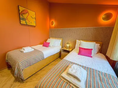 two beds in a room with orange walls at Blackthorn Timber Lodge in Bothel