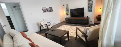 a living room with a couch and a tv at The Spacious Urban Retreat in Douglas