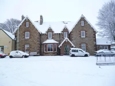 a large brick building with cars parked in the snow at The Hopetoun Arms Hotel in Leadhills