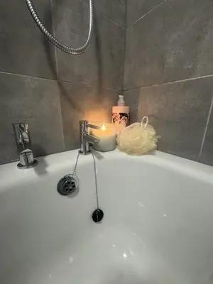 a candle sitting on the edge of a bath tub at West Lakes 3 Bedroom - Sleeps 5 - Self Check In - Fully Furnished House in Workington
