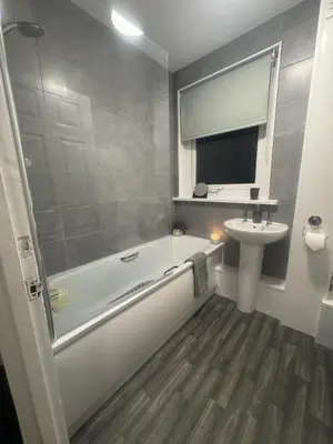 a bathroom with a white tub and a sink at West Lakes 3 Bedroom - Sleeps 5 - Self Check In - Fully Furnished House in Workington