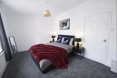 a bedroom with a bed with a red blanket at Mid Street Retreat, Steps from the Beach, Whitehaven in Whitehaven