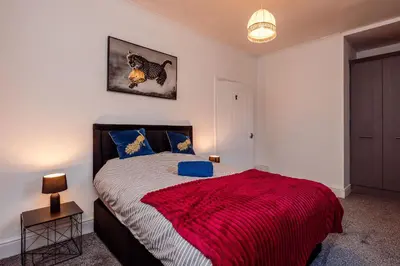 a bedroom with a large bed with a red blanket at Mid Street Retreat, Steps from the Beach, Whitehaven in Whitehaven