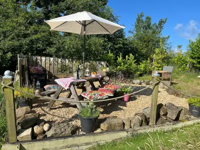 a picnic table with an umbrella in a garden at Handy for Lake District, detached property in Penruddock