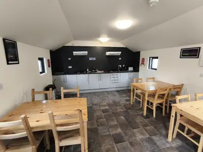 a dining room with wooden tables and a kitchen at Barrhill Holiday Park - Glamping in South West Scotland - Stinchar in Girvan