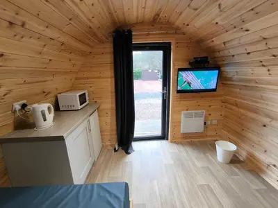 a room with a kitchen and a tv in a cabin at Barrhill Holiday Park - Glamping in South West Scotland - Stinchar in Girvan