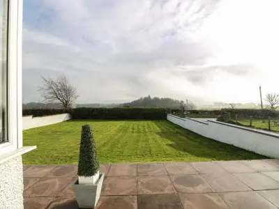 a view of a grassy yard with a wall at Marchdyke Farm Cottage in Lockerbie