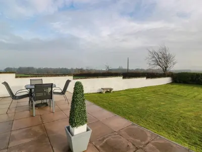 a patio with a table and chairs and a lawn at Marchdyke Farm Cottage in Lockerbie