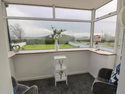 a room with a window with a vase with flowers in it at Marchdyke Farm Cottage in Lockerbie