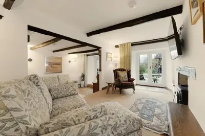 a living room with a couch and a fireplace at Walthwaite How Cottage in Chapel Stile